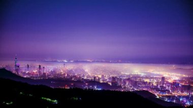 Taipei şehrinde beyaz bulutlar ve sis tabakası, şehir ışıklarıyla birlikte, renkli bir ışık oluşturur..