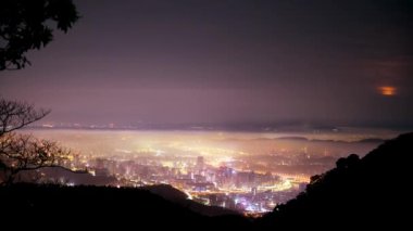 Taipei şehrinde beyaz bulutlar ve sis tabakası, şehir ışıklarıyla birlikte, renkli bir ışık oluşturur..