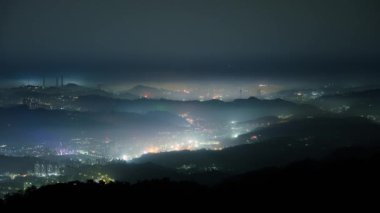 Datun Dağı 'ndan bakıldığında şehir beyaz bulut ve sis tabakasıyla kaplıdır. Şehir ışıklarıyla birlikte renkli cam bir ışık oluşturuyor..