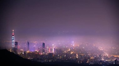 Taipei şehrinde beyaz bulutlar ve sis tabakası, şehir ışıklarıyla birlikte, renkli bir ışık oluşturur..
