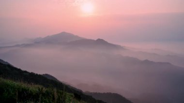 Batan güneş parlak turuncu renkte bir sis perdesi oluşturarak dağda geniş bir renkli duvar halısı oluşturur. Buyan Pavyonu, New Taipei Şehri.