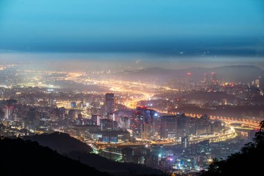 Taipei şehrinde beyaz bulutlar ve sis tabakası, şehir ışıklarıyla birlikte, renkli bir ışık oluşturur..