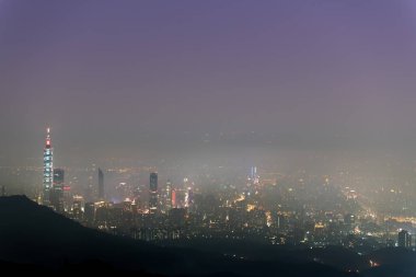 Taipei şehrinde beyaz bulutlar ve sis tabakası, şehir ışıklarıyla birlikte, renkli bir ışık oluşturur..