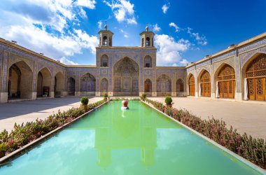 İran 'ın Şiraz kentindeki Nasir Al-Mulk Camii' nde sakin bir öğleden sonra, avlu havuzunun, yedi renkli fayans desenlerinin ve Pers kemerlerinin ve pencerelerinin sergilendiği.