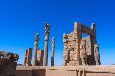 Lamassu heykelleri, Persepolis, İran 'ın antik harabeleri arasında karmaşık gölgeler bırakarak dimdik ayakta duruyor. Mavi gökyüzü ve bulutlarla aydınlık bir günde yakalandı..