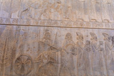 İnsanları ve hayvanları hareket halindeyken gösteren detaylı taş oymaları. Antik sanat eserlerine bir bakış, karmaşık tasarımlar ve hikaye anlatımları, Persepolis, İran.