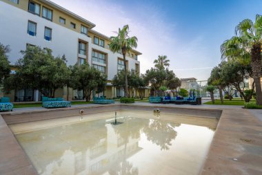Essaouira, Fas - 17 Mart 2024: Boş ve temiz yüzme havuzu ve yemyeşil bahçeleri olan lüks bir otelin dış görünüşü.