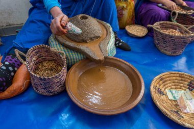 Essaouira, Fas - 17 Mart 2024: Yerel kadınlar geleneksel argan yağı çıkarma sanatıyla meşgul. Sahne, yerel kültür gelenekleri ve kırsal cazibeyi yansıtıyor.