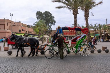 Jemaa el-Fnaa, Marakeş, Fas - 18 Mart 2024: Geleneksel at arabaları ve çekçekçekçekli araçlar yolcuları bekliyor.