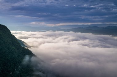 Güneş ışığı bulutların denizini tahmin edilemez bir şekilde değiştiriyor, fırtınalı dalgalar gibi. Zümrüt Rezervuar 'ı çevreleyen dağların manzarası. Xindian Bölgesi, Tayvan.