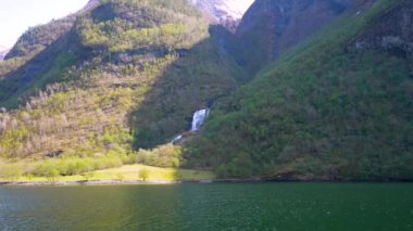 Yol boyunca karlı dağlar, şelaleler ve göl yansımaları var. Dünya Mirası Sognefjord 'u gezin ve güzel manzaranın tadını çıkarın. Norveç.