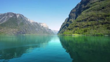 Yol boyunca karlı dağlar, şelaleler ve göl yansımaları var. Dünya Mirası Sognefjord 'u gezin ve güzel manzaranın tadını çıkarın. Norveç.