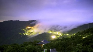 Gece yarısı gökyüzünde bulutlar. Dağın tepesinde bulut şelalesi. Zümrüt Rezervuar 'ı çevreleyen dağların manzarası. Xindian Bölgesi, Tayvan.