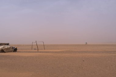 Bir toz fırtınası sırasında Merzouga 'nın kumlu ovalarında bir araba hız yapar; görüş mesafesi bir sise indirgenir. Geçici barınak görünüyor, Fas.