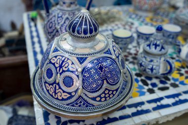 Fes, Fas - 23 Mart 2024: Detaylı mavi ve beyaz desenli, çeşitli çanak çömlek üretim aşamalarıyla çevrili güzel hazırlanmış bir tencereye yakından bakmak.