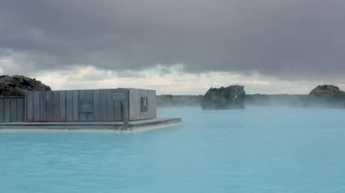 İzlanda 'daki Mavi Göl' ün süt mavisi suları siyah lav kayaları ve liken ile tezat oluşturur; barışçıl bir jeotermal kaplıca sahnesi. Reykjanes Yarımadası, İzlanda.