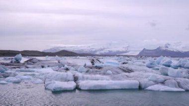 Mavi ve beyaz buzdağları buzul zeminine karşı buzul gölünde yüzerek huzur verici bir manzara yaratırlar. Bozulmamış Jokulsarlon, İzlanda.