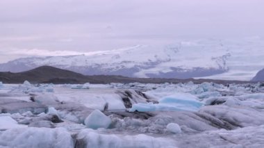 Mavi ve beyaz buzdağları buzul zeminine karşı buzul gölünde yüzerek huzur verici bir manzara yaratırlar. Bozulmamış Jokulsarlon, İzlanda.
