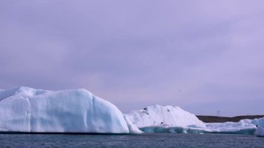 Mavi ve beyaz buzdağları buzul zeminine karşı buzul gölünde yüzerek huzur verici bir manzara yaratırlar. Bozulmamış Jokulsarlon, İzlanda.