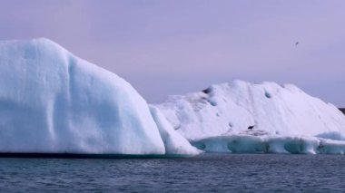 Mavi ve beyaz buzdağları buzul zeminine karşı buzul gölünde yüzerek huzur verici bir manzara yaratırlar. Bozulmamış Jokulsarlon, İzlanda.