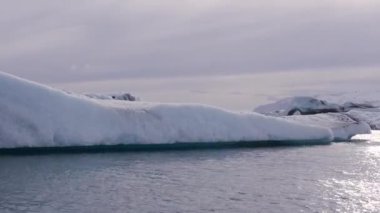 Mavi ve beyaz buzdağları buzul zeminine karşı buzul gölünde yüzerek huzur verici bir manzara yaratırlar. Bozulmamış Jokulsarlon, İzlanda.