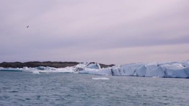 Mavi ve beyaz buzdağları buzul zeminine karşı buzul gölünde yüzerek huzur verici bir manzara yaratırlar. Bozulmamış Jokulsarlon, İzlanda.