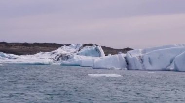Mavi ve beyaz buzdağları buzul zeminine karşı buzul gölünde yüzerek huzur verici bir manzara yaratırlar. Bozulmamış Jokulsarlon, İzlanda.
