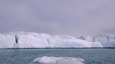 Mavi ve beyaz buzdağları buzul zeminine karşı buzul gölünde yüzerek huzur verici bir manzara yaratırlar. Bozulmamış Jokulsarlon, İzlanda.