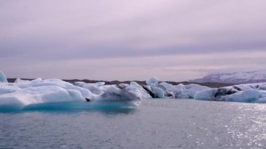 Mavi ve beyaz buzdağları buzul zeminine karşı buzul gölünde yüzerek huzur verici bir manzara yaratırlar. Bozulmamış Jokulsarlon, İzlanda.