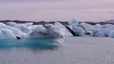 Mavi ve beyaz buzdağları buzul zeminine karşı buzul gölünde yüzerek huzur verici bir manzara yaratırlar. Bozulmamış Jokulsarlon, İzlanda.