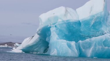 Mavi ve beyaz buzdağları buzul zeminine karşı buzul gölünde yüzerek huzur verici bir manzara yaratırlar. Bozulmamış Jokulsarlon, İzlanda.