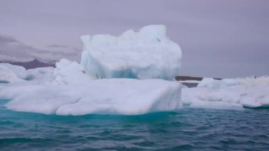 Mavi ve beyaz buzdağları buzul zeminine karşı buzul gölünde yüzerek huzur verici bir manzara yaratırlar. Bozulmamış Jokulsarlon, İzlanda.