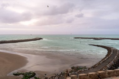 Udayas 'lı Kasbah' tan okyanusun üzerindeki gün batımı manzarası. Güneş ışığı bulutların arasından bakıyor, Rabat, Fas.