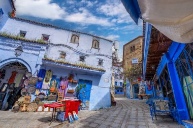 Chefchaouen, Fas - 25 Mart 2024: Mavi boyalı sokaklarda renkli seramik tabaklar ve aynalar sergilenen bir el işi dükkanı.
