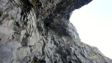 Düzensiz şekilli bazalt sütunlar ve deniz mağarası. Volkanik kum, Vik, İzlanda. Kara Kum Sahili dünyanın en güzel on plajından biri olarak seçildi..