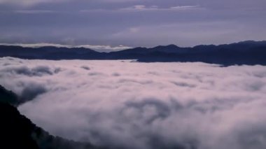 Dolunayın, okyanus dalgalarına benzeyen engin bir bulut denizini aydınlattığı sakin bir manzara. Gökyüzü yıldızlarla kaplı ve sakin bir ortam yaratıyor. Xindian Bölgesi, Tayvan.