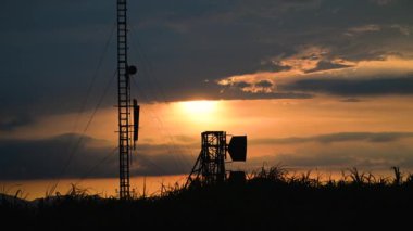 Canlı bir günbatımı bir kıyı radar istasyonu üzerinde sarı ve turuncu renklerin bir karışımını gösterir. Radar ekipmanlarının silueti renkli gökyüzü ve uzak dağlar Tayvan ile çelişiyor..