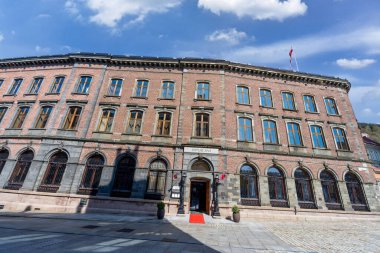Bergen, Norveç - 30 Nisan 2024: Şehir merkezinde tarihi bir bina olan Hotel Opus XVI manzarası. Otel, kemerli pencereli ve Norveç bayrağıyla süslenmiş klasik bir tuğla cepheye sahip..