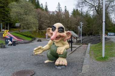 Bergen, Norveç - 30 Nisan 2024: Renkli bir trol heykeli Norveç parkına ziyaretçileri kabul ediyor. Dost canlısı dev, oyun alanı ekipmanları ve yemyeşil alanlarla çevrili..