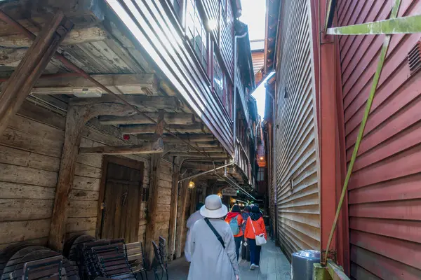 stock image Bergen, Norway - April 30, 2024: Tourists visit a narrow alley lined with colorful wooden houses in the historic Bryggen district of Bergen.