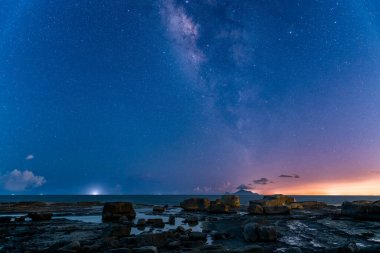 Gece deniz manzarası, baş döndürücü bir galaksisi, yıldızlı gökyüzü ve ara sıra yıldırımı olan Kaplumbağa Adası. Romantik ve dramatik gece gökyüzü, Yilan County, Tayvan.
