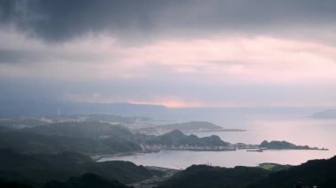 Dağın tepesinden, dumanla örtülü bir manzara beliriyor ve yuvarlanan tepelerin arasına yerleşmiş pitoresk bir kıyı köyünü gösteriyor. Jiufen, Tayvan.