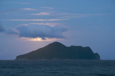 Geceleri Ay, Kaplumbağa Adası üzerinde yavaşça yükselir ve aniden bulutlar tarafından gizlenir ve Pasifik Okyanusu 'nun sakin sularına maruz kalır. Yilan County, Tayvan.
