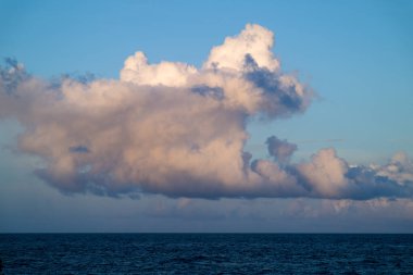 Güneşli bir öğleden sonra, kümülüs bulutları Pasifik Okyanusu boyunca devasa gölgeler bıraktı. Bulutların tabanı ufuk çizgisine kayar, ölçek ve merak duygusu yaratır. Yilan County, Tayvan.