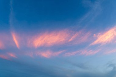 Gün batımı gökyüzünün nefes kesici manzarası, açık mavi bir tuval üzerinde pembe ve turuncu renkli canlı renkler sergiliyor. Touchen, Yilan County, Tayvan.