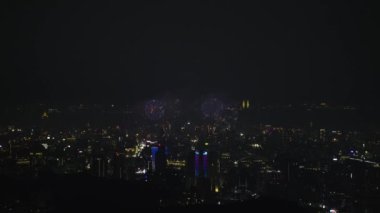 Göz kamaştırıcı havai fişekler canlı şehir manzarasını aydınlatıyor. Taipei 'nin silueti karanlık gece gökyüzünde renkli patlamalarla süslenmiş. Dajianshan, Tayvan.