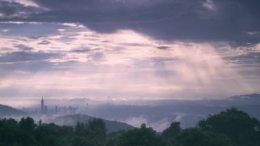 Taipei şehrinin kısmen bulutlarla kaplı siluetinin nefes kesici panoramik görüntüsü. Altın güneş ışınları bulutlu gökyüzünü delip geçer ve şehir manzarasına sıcak bir ışık saçar. Tayvan.