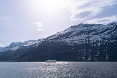 Feribot, Hardangerfjord 'un sakin sularından geçiyor. Arka planda karla kaplı dağlar var, nefes kesici. Voss, Norveç.