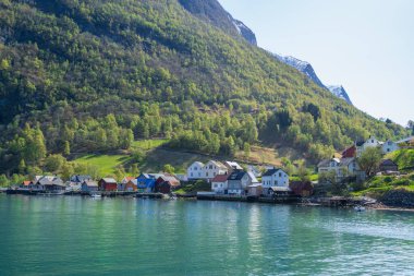 Huzurlu bir Norveç fiyordunun kıyılarına kurulmuş pitoresk bir köy. Geleneksel ahşap evler ve küçük bir kilise yemyeşil dağlar ve berrak mavi sularla çevrilidir. Sognefjord, Norveç.