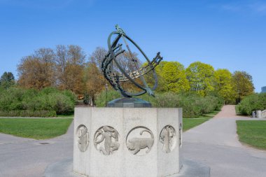 Oslo, Norveç - 3 Mayıs 2024: Vigeland Heykel Parkı 'nın dairesel meydanının merkezinde bronz bir güneş saati duruyor. Bereketli yeşilliklerle çevrili olan güneş saati odak noktası haline gelir..